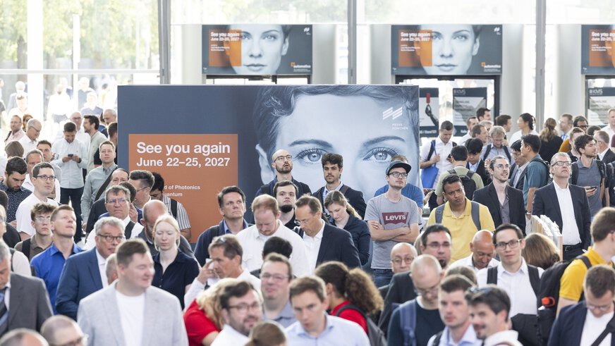 Zahlreiche Messebesucher bewegen sich durch das lichtdurchflutete Eingangsfoyer der Messe München. Im Mittelpunkt steht ein großes Plakat mit dem Hinweis „See you again – June 22–25, 2027“.