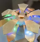 Futuristic metal flower sculpture with multicolored LED lights on each petal.