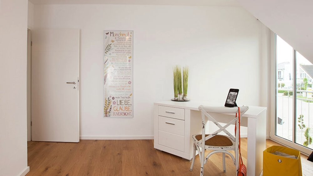 Minimalistischer Raum mit weißen Wänden, einem kleinen Tisch mit Stuhl, einer grünen Pflanze, Wandkunst und einem Fenster mit Sonnenlicht.