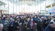 Blick in die Eingangshalle einer Messe, wo viele Besucher an den Drehkreuzen anstehen.