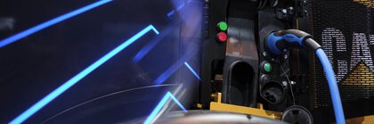 Charging station for an electric vehicle in neon blue light with a connected Caterpillar vehicle.