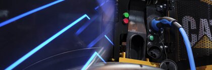 Charging station for an electric vehicle in neon blue light with a connected Caterpillar vehicle.