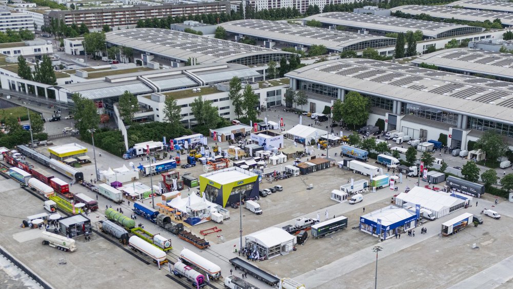 Bird's eye view of the open-air site of Messe München during transport logistic with exhibitor stands and railway carriages next to it.