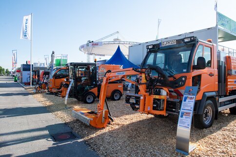 Freiluftausstellung von Baumaschinen mit orangefarbener Ausrüstung und blauen Zelten.