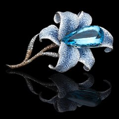 Close-up of a blue elongated gemstone in the center of a blue decorative flower with a brownish stem.