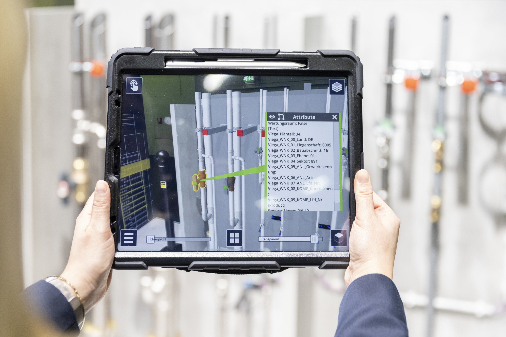 Zwei Hände halten ein Tablet, das technische Überwachungdaten von Gebäuden anzeigt.