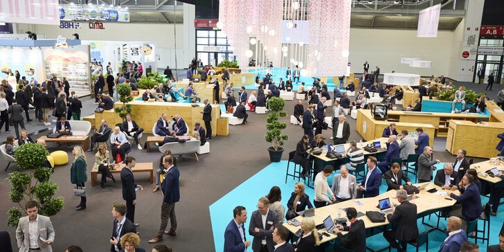 In einem weitläufigen Arbeits- und Meetingbereich der EXPO REAL arbeiten und unterhalten sich zahlreiche Messebesucher.