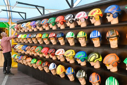 A wall of shelves full of mannequin heads with safety goggles and bright safety helmets in a wide variety of colours.