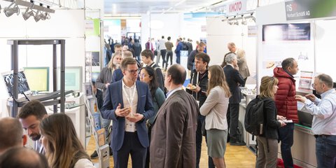 A well-attended LOPEC trade fair where people interact with each other in the exhibition space and explore the exhibitors' stands.