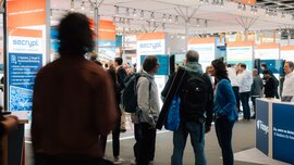 Ausstellungsbereich der DMEA mit Ständen, Gesprächen und Besuchern in einer Messehalle