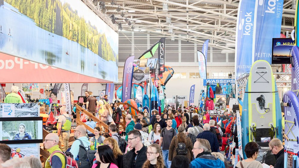 Zahlreiche Besucher laufen zwischen Ausstellungsständen mit bunten Werbebannern und Mitmachbereichen der f.re.e in einer Halle der Messe München entlang.