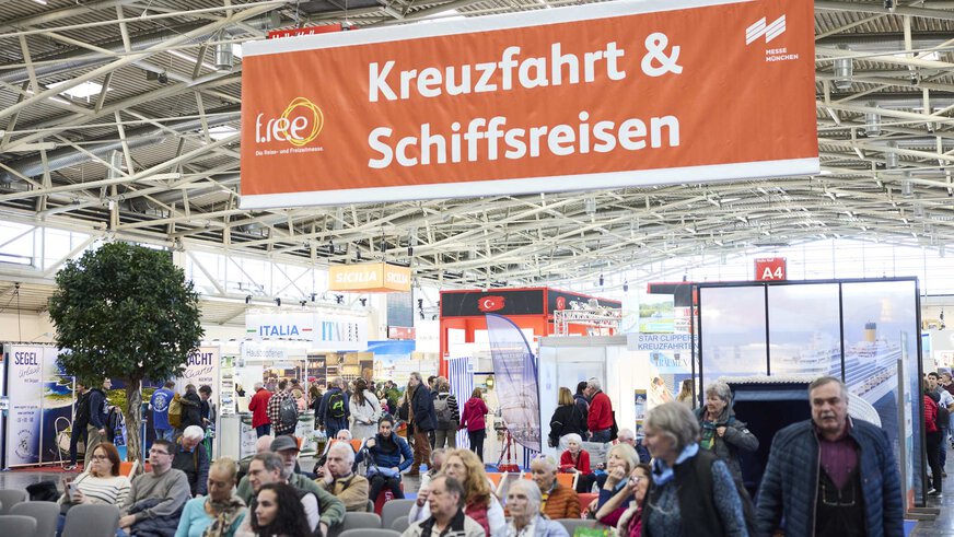 “Cruise & Ship Travel” exhibition area at f.re.e with visitors, seats and stands for cruises and yacht travel.