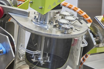 Close-up of a ceramic machine with transparent container and metal components.