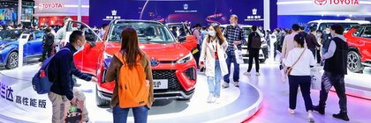 Zahlreiche Besucher auf der AUTO SHANGHAI Messe stehen zwischen einzelnen Messeständen und betrachten die ausgestellten Autos.