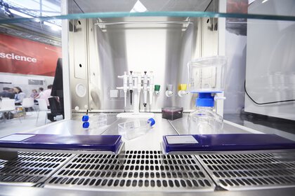 Ein steriler Laborarbeitsplatz aus Edelstahl gefertigt und ausgestattet mit Pipetten, Probenbehälter und anderen Labormaterialien.
