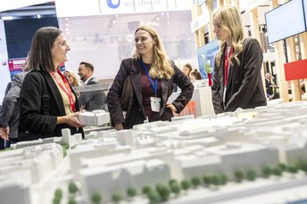 Drei Frauen im Gespräch an einem Messestand.