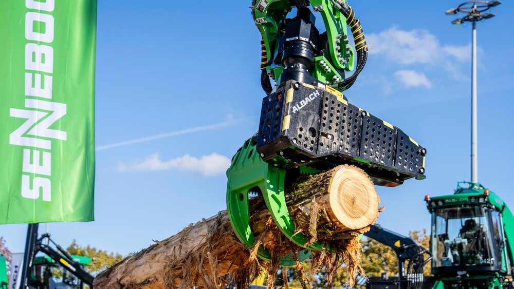 Ein mechanischer Greifer von Albach hebt einen großen Baumstamm an.