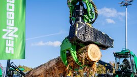 Ein mechanischer Greifer von Albach hebt einen großen Baumstamm an.