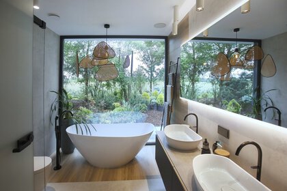 Modernes Badezimmer mit freistehender Badewanne, großem Fenster mit Blick ins Grüne, Doppelwaschbecken und zeitgenössischer Einrichtung.