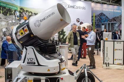 People at an exhibition stand discuss a large water mist cannon on display.