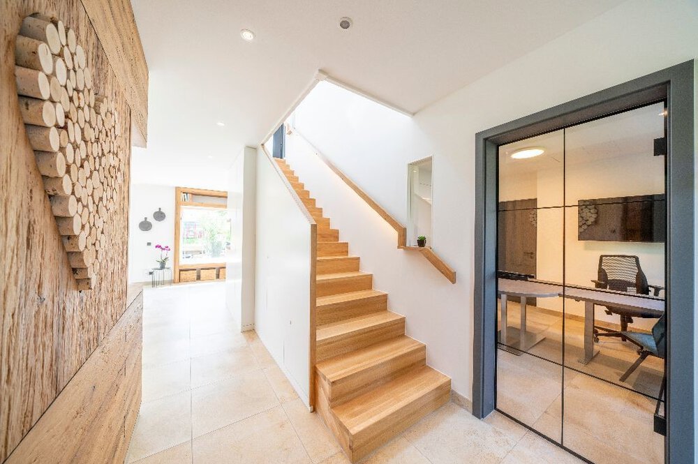 Modernes Interieur mit Holztreppe, Glasbürotür und dekorativer Holzblockwandstruktur.
