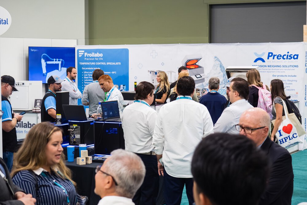 People who network and visit exhibition stands at a science and technology fair.