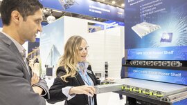 An exhibitor pulls one of six modules out of a server rack and demonstrates it to a visitor.