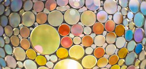 Ein kuppelartiges Mosaik aus bunten, runden Glasscheiben in verschiedenen Größen, durch die Licht scheint.