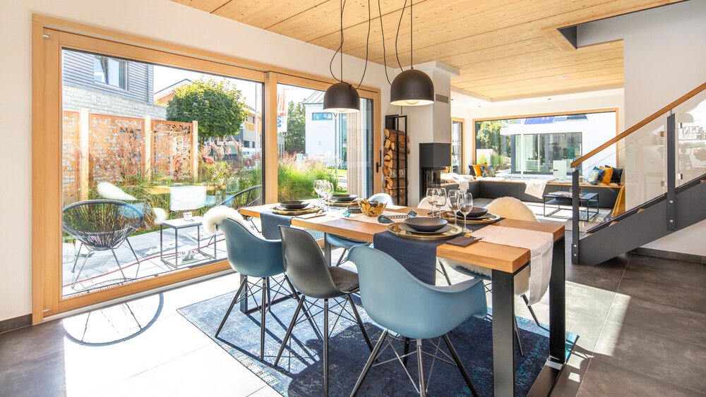 Moderner Essbereich mit Holztisch, grauen Stühlen und großen Glastüren zum Garten. Hell und geräumig.