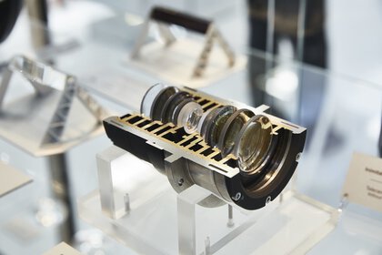 A cross-section model of a lens, presented on a transparent stand.