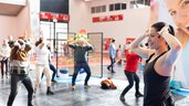 Eine Gruppe von Menschen macht Yoga Übungen in einer Messehalle