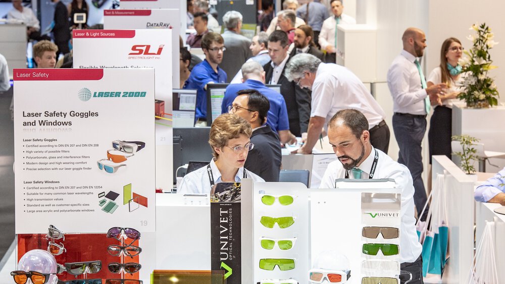 People at an exhibition stand displaying various laser safety goggles and glasses.