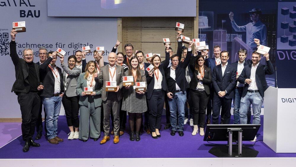 Viele Menschen stehen lächelnd auf der Bühne der digitalBAU und halten Auszeichnungen in die Höhe.