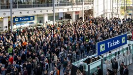 Large crowd of visitors in an exhibition entrance hall in front of the ticket counters.