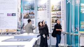 Eine Gruppe von Messebesuchern steht an einem Stand auf der BAU CHINA zwischen riesigen Informationstafeln und blickt hinauf.