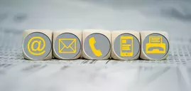 Fünf Würfel nebeneinander mit gelben Symbolen auf der Vorderseite: E-Mail, Brief, Telefon, Handy und Fax.