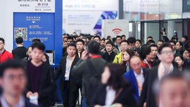 Numerous visitors to Messe München Shanghai move through the entrance area, past a blue stele bearing the words “Visitor Registration”.