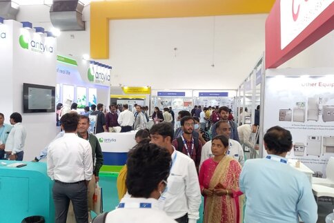 Well-attended trade fair with several booths for laboratory and scientific equipment, where many attendees are engaged in conversations.
