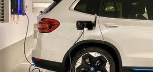 White SUV electric vehicle is parked at a station in a parking garage.
