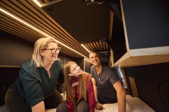 Eltern mit Kind schauen sich begeistert einen ausgebauten Camper-Van von innen an.