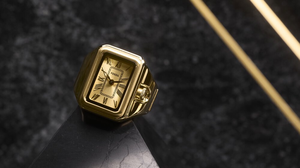 Golden clock with Roman numerals on a black marble surface and diagonal golden lines in the background.