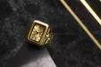 Golden clock with Roman numerals on a black marble surface and diagonal golden lines in the background.