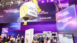 Visitors marvel at a large mobile 3D printer with colourful lighting and several displays.