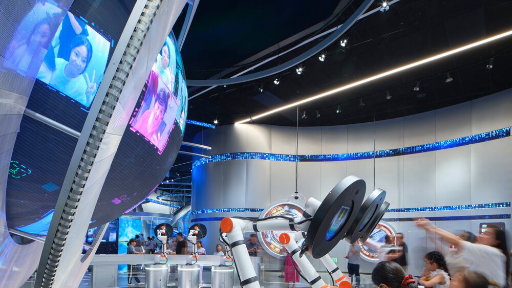 A large silver-framed globe with several video stations in front of it, where visitors are filmed and projected onto the globe.