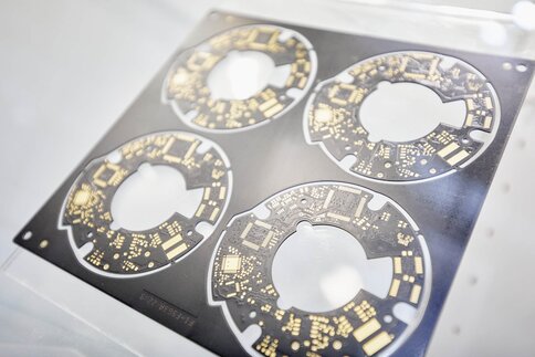 Close-up of four identical round circuit boards still hanging in a black die-cut mould.