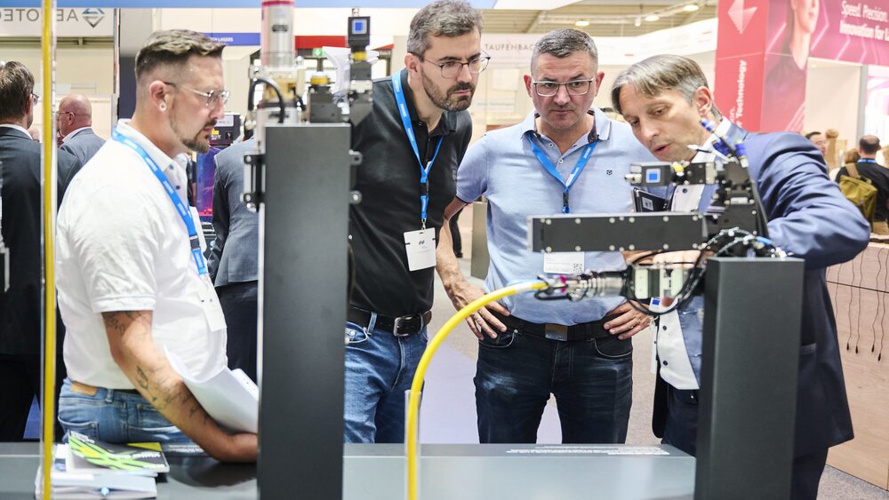 Vier Männer betrachten ein technisches Exponat auf der Laser World of Photonics 2025 in München.