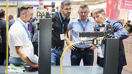 Vier Männer betrachten ein technisches Exponat auf der Laser World of Photonics 2025 in München.
