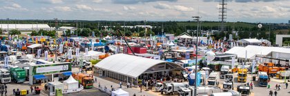 Bird's eye view of the IFAT Munich open-air grounds, with numerous stands, trucks and visitors. The trade fair tower can be seen in the background.