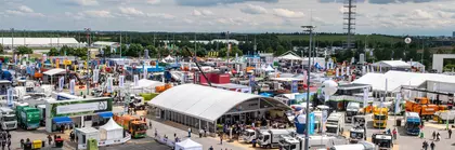 Vogelperspektive des IFAT Munich Freigeländes, mit zahlreichen Ständen, Trucks und Besuchern. Im Hintergrund ist der Messeturm zu sehen.