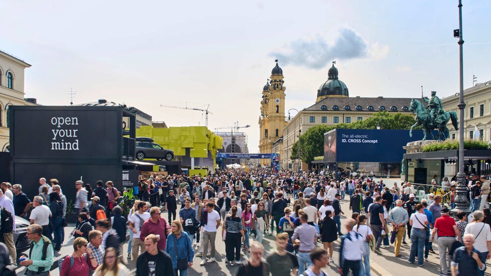 Zahlreiche Messebesucher besuchen Messestände der IAA Mobility auf dem Odeonsplatz in München. Im Hintergrund ist die Theatinerkirche zu sehen.